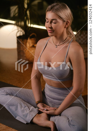 Practicing yoga in a serene indoor space with soft lighting and plants during the evening hours 124032414