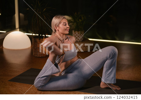 Practicing yoga in a serene indoor space with soft lighting and plants during the evening hours 124032415