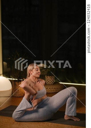 Practicing yoga in a serene indoor space with soft lighting and plants during the evening hours 124032416