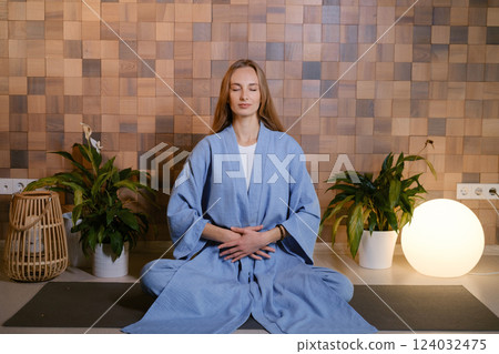 Girl in blue kimano practicing kundalini or qigong yoga in fitness gym . Spiritual energy, life force located at the base of the spine 124032475