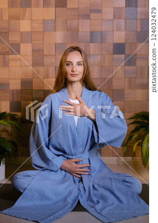 Girl in blue kimano practicing kundalini or qigong yoga in fitness gym . Spiritual energy, life force located at the base of the spine Girl in blue kimano practicing kundalini or qigong yoga in fitness gym . Spiritual energy, life force located at the base of the spine 124032479