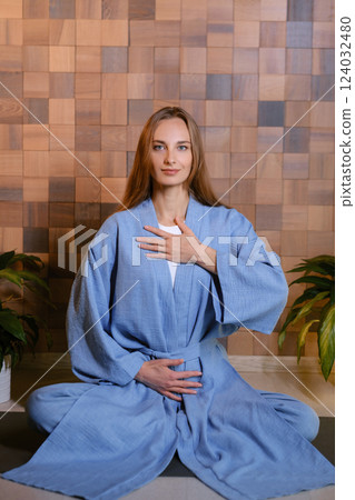 Yoga instructor in blue kimano at fitness gym . The girl does qigong yoga. The exercises are based on the movement of internal energy, the system of channels, energy centers, chakras 124032480