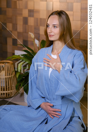 Girl in blue kimano practicing kundalini or qigong yoga in fitness gym . Spiritual energy, life force located at the base of the spine Girl in blue kimano practicing kundalini or qigong yoga in fitness gym . Spiritual energy, life force located at the base of the spine 124032481