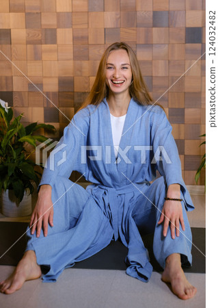 Girl in blue kimano practicing kundalini or qigong yoga in fitness gym . Spiritual energy, life force located at the base of the spine Girl in blue kimano practicing kundalini or qigong yoga in fitness gym . Spiritual energy, life force located at the base of the spine 124032482