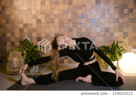 Athletic girl in black sportswear doing yoga in fitness room among indoor green plants Athletic girl in black sportswear doing yoga in fitness room among indoor green plants 124032521