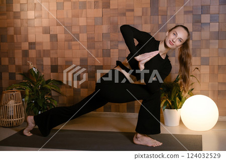 Yoga instructor in black sportswear demonstrates an element of yoga exercise in a fitness gym Yoga instructor in black sportswear demonstrates an element of yoga exercise in a fitness gym 124032529