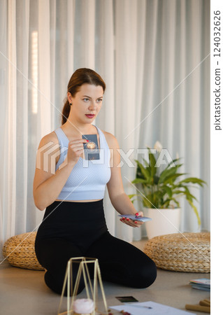 A sporty girl lays out Tarot cards indoors. Tarot cards in the hands of a fortune teller A sporty girl lays out Tarot cards indoors. Tarot cards in the hands of a fortune teller 124032626