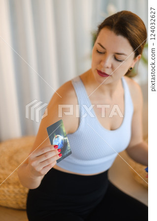 A sporty girl lays out Tarot cards indoors. Tarot cards in the hands of a fortune teller 124032627