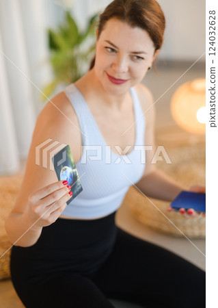 A sporty girl lays out Tarot cards indoors. Tarot cards in the hands of a fortune teller 124032628