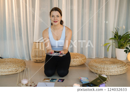 A sporty girl lays out Tarot cards indoors. Tarot cards in the hands of a fortune teller 124032633