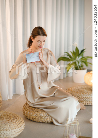 Girl in beige dress with beads with a fan of Tarot cards indoors . Tarot cards in the hands of a fortune teller 124032654