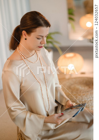 A diviner girl in a beige dress with beads with tarot cards in the room. Tarot cards in the hands of a fortune teller A diviner girl in a beige dress with beads with tarot cards in the room. Tarot cards in the hands of a fortune teller 124032657