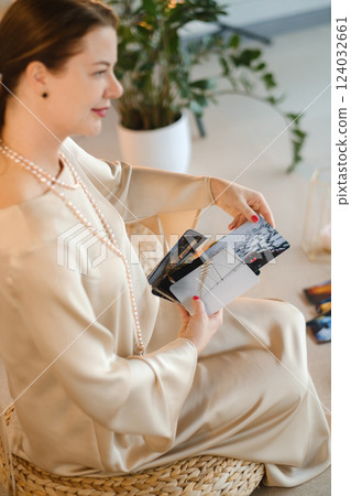 Girl in beige dress with beads with a fan of Tarot cards indoors . Tarot cards in the hands of a fortune teller 124032661