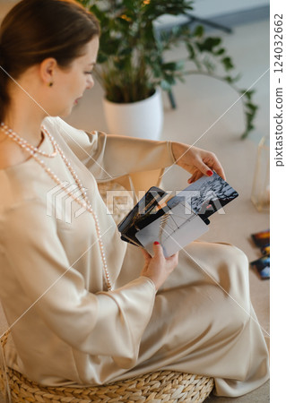 Girl in beige dress with beads with a fan of Tarot cards indoors . Tarot cards in the hands of a fortune teller 124032662