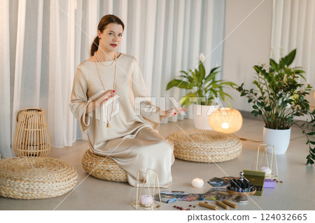 A diviner girl in a beige dress with beads with tarot cards in the room. Tarot cards in the hands of a fortune teller 124032665