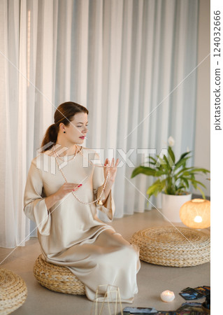 Beautiful Girl in beige dress and beads sitting indoors in front of practice Beautiful Girl in beige dress and beads sitting indoors in front of practice 124032666