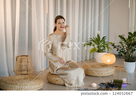Beautiful Girl in beige dress and beads sitting indoors in front of practice 124032667