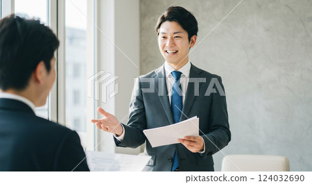 A reliable male office worker showing materials and explaining to his boss or client Presentation 124032690