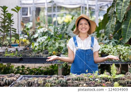Happy female gardener in green house full of plants 124034909