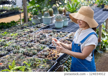 Happy female gardener in green house with mobile augmented reality 124034912