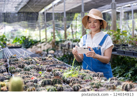 Happy female gardener in green house with mobile augmented reality 124034913