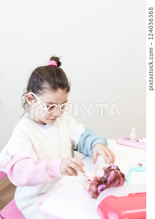 Child playing doctor with doll 124036368