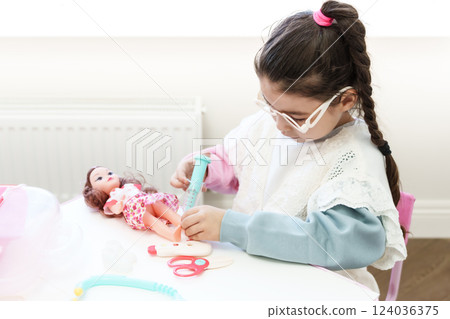 Child playing doctor with doll Child playing doctor with doll 124036375
