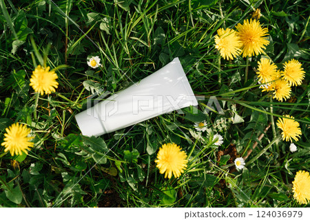 White Cosmetic Tube in Grass with Yellow Dandelions White Cosmetic Tube in Grass with Yellow Dandelions 124036979