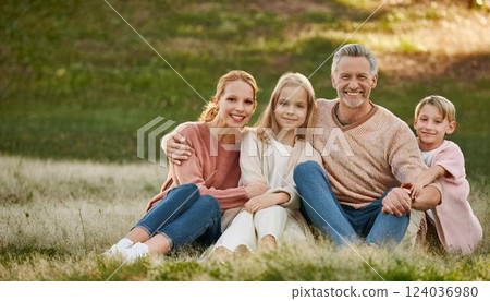 Happy family of six with grandparents sitting in park, embracing and smiling at camera 124036980