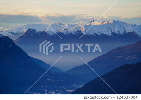 Misty Mountain Valley with Snow-Capped Peaks at Dusk near Piani di Bobbio in Italy Misty Mountain Valley with Snow-Capped Peaks at Dusk near Piani di Bobbio in Italy 124037004