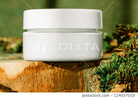 Jar of firming cream with collagen placed on round wooden display on green earthy toned background 124037010