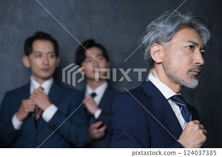 A gray-haired businessman tightening his tie as he heads to a business meeting. A complex of executive images such as enthusiasm and success. 124037385