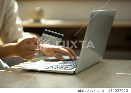 Close up of woman holding a credit card and typing on laptop, internet banking, or secure digital purchases. Close up of woman holding a credit card and typing on laptop, internet banking, or secure digital purchases. 124037450