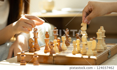 Close up of friends playing chess under warm natural light 124037462