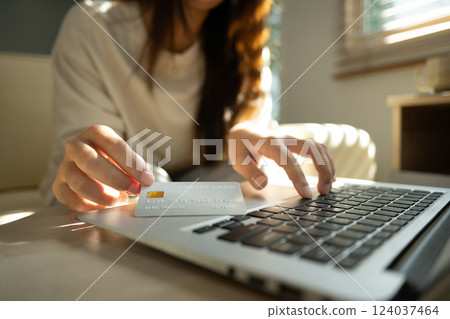 Close up of woman holding a credit card and typing on laptop, internet banking, or secure digital purchases. 124037464
