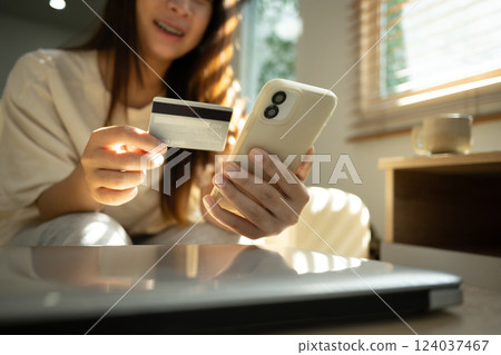 Happy young woman making an online purchase using her mobile phone and credit card Happy young woman making an online purchase using her mobile phone and credit card 124037467