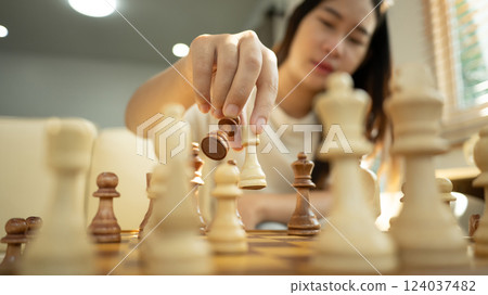 Close up shot of a woman hand placing a chess piece on board 124037482