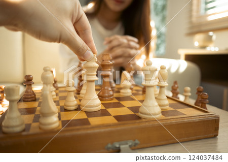 Close up of hand moves a chess piece on a classic wooden chessboard Close up of hand moves a chess piece on a classic wooden chessboard 124037484