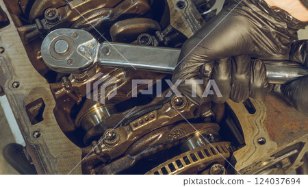 A mechanic working on a car engine in a well-equipped auto repair shop. Car Engine Repair. Mechanic using wrench while working on car engine at garage workshop. Repairing engine in auto repair shop A mechanic working on a car engine in a well-equipped auto repair shop. Car Engine Repair. Mechanic using wrench while working on car engine at garage workshop. Repairing engine in auto repair shop 124037694