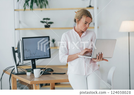 Using smartphone to communicate. Female stock broker in formal wear is working in the office Using smartphone to communicate. Female stock broker in formal wear is working in the office 124038028