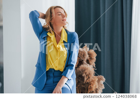 Woman in formal blue and yellow colored trouser suit is indoors 124038068