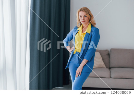 Woman in formal blue and yellow colored trouser suit is indoors Woman in formal blue and yellow colored trouser suit is indoors 124038069