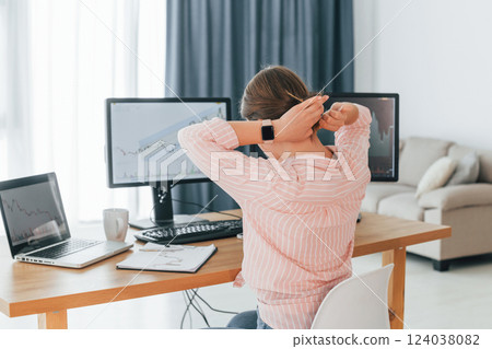 Rear view. Female stock broker in casual clothes is working in the office by pc Rear view. Female stock broker in casual clothes is working in the office by pc 124038082