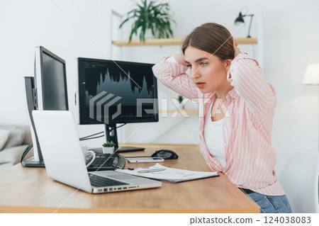 Shocked look. Female stock broker in casual clothes is working in the office by pc Shocked look. Female stock broker in casual clothes is working in the office by pc 124038083