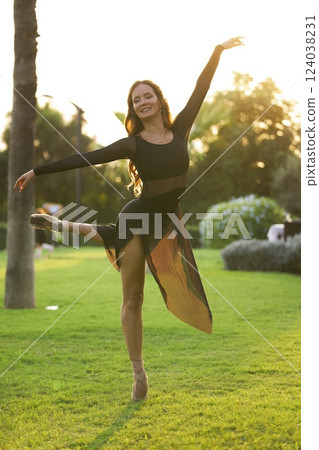 Ballerina performing graceful dance pose at sunset  124038231