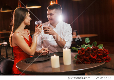 Sitting with drinks by the table together. Romantic couple have dinner in the restaurant Sitting with drinks by the table together. Romantic couple have dinner in the restaurant 124038588