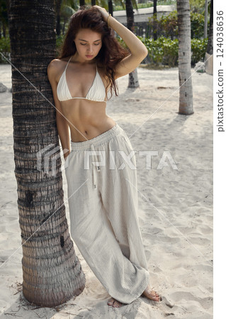 young brunette woman walking on the sand. Beautiful girl under palm on a beach 124038636