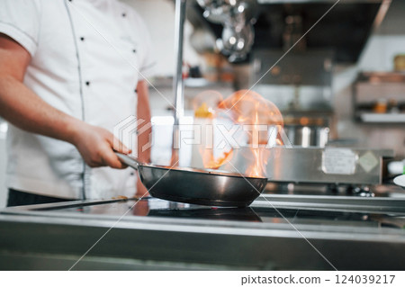 Method of cooking by igniting meal. Professional chef preparing food in the kitchen 124039217
