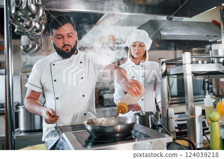 Woman and man woking together. Professional chef preparing food in the kitchen 124039218