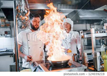 Igniting food in the frying pan. Professional chef preparing food in the kitchen 124039219